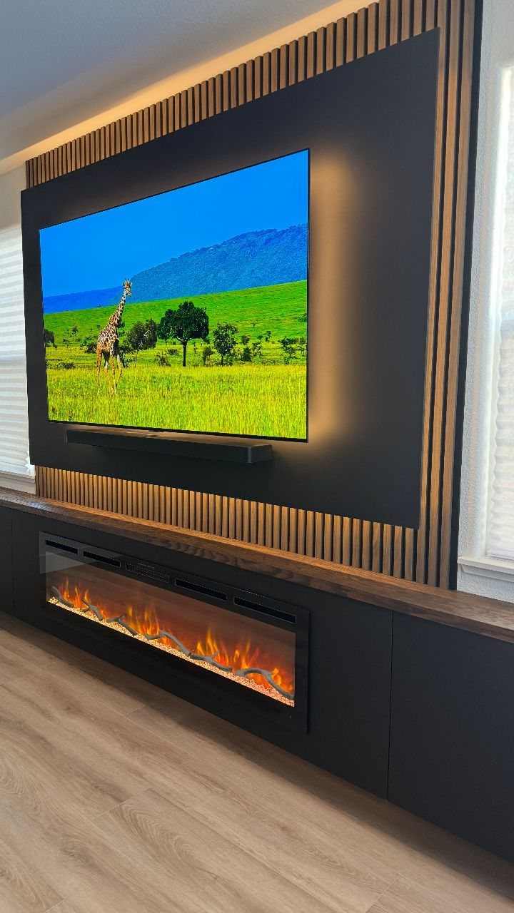 Vertical light wood slats framing a black accent wall with a television and electric fireplace.