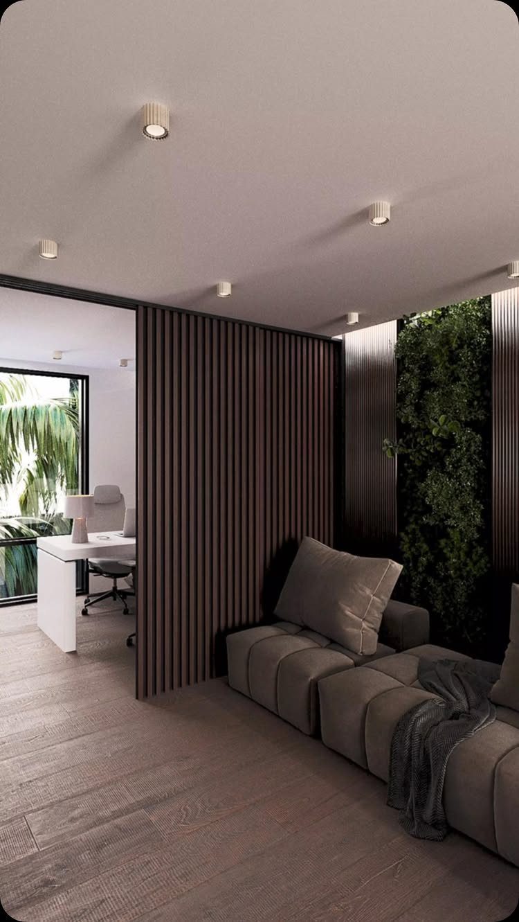 Dark wood slatted partition wall separating a living room from a bright home office space.