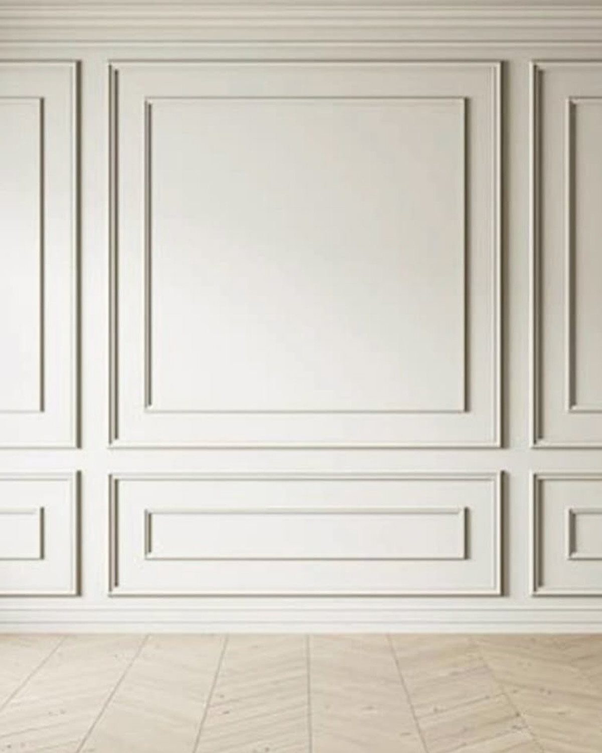 Decorative beige box moulding panels on a wall above a light herringbone wood floor.