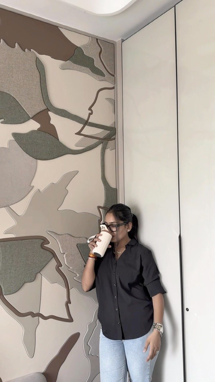 Woman standing next to a wall featuring large, abstract-shaped textured panels in neutral tones.