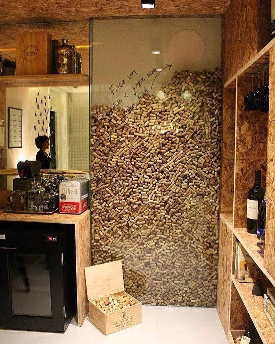 A large glass partition filled with wine corks located in a wooden bar setting.