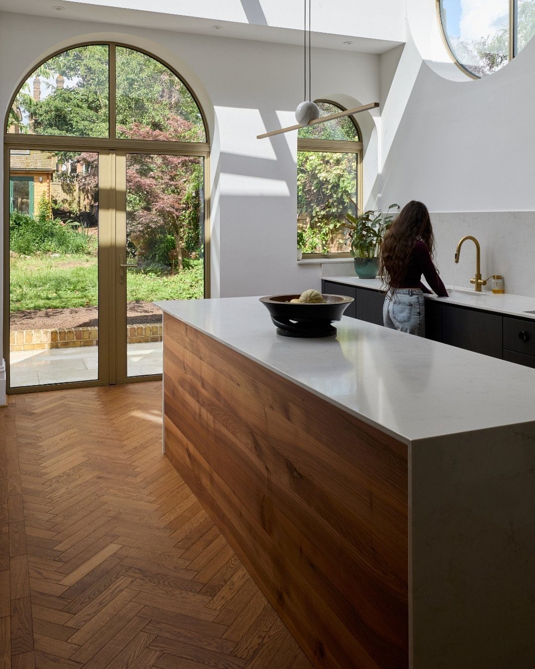 Herringbone patterned wood flooring in a bright, modern kitchen with a large wooden island.