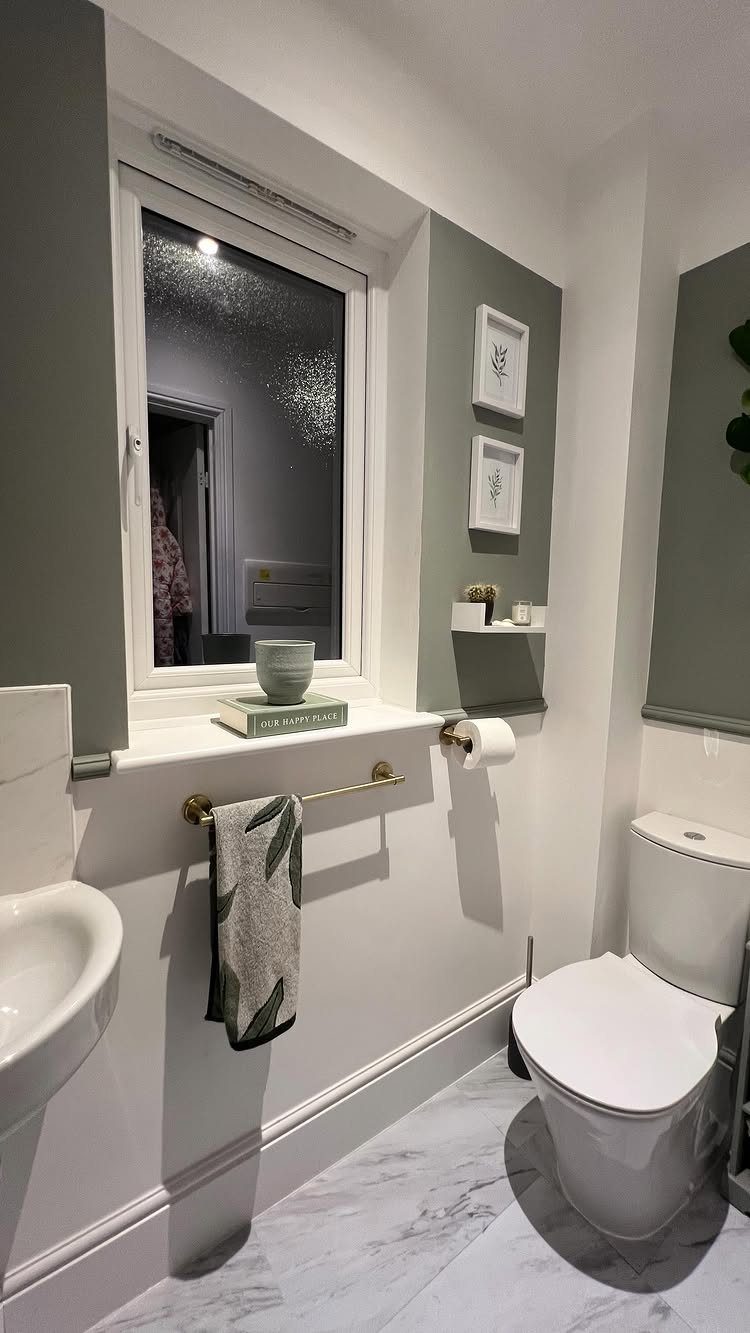 White marble-patterned floor tiles in a bathroom with a toilet and sage green walls.