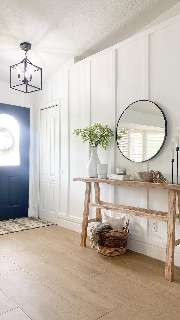 Light wood-look floor tiles in a bright entryway with white paneled walls and a wooden console table.