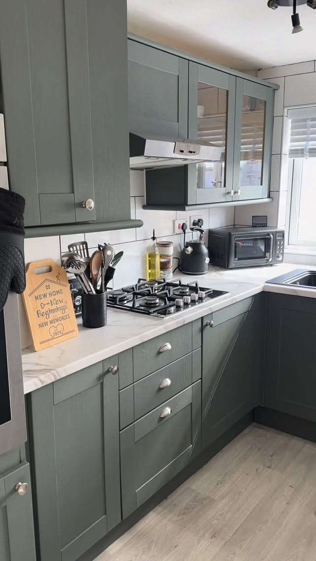 Light grey wood-effect vinyl flooring in a modern sage green kitchen setting.