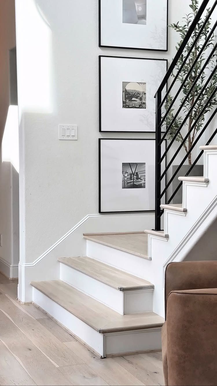 Light wood-look flooring on the ground and staircase treads next to a white wall with framed art.