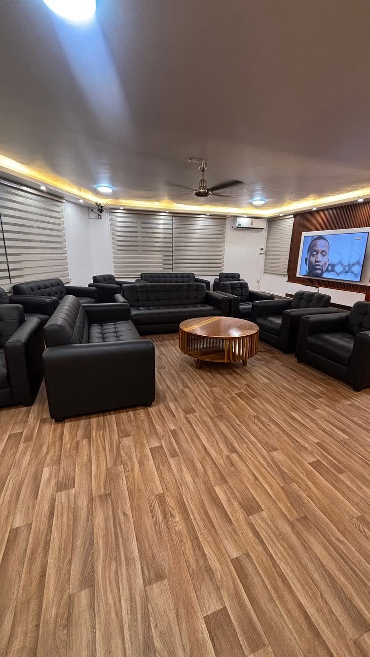Wood-look vinyl flooring in a living room with black leather sofas and a wooden coffee table.