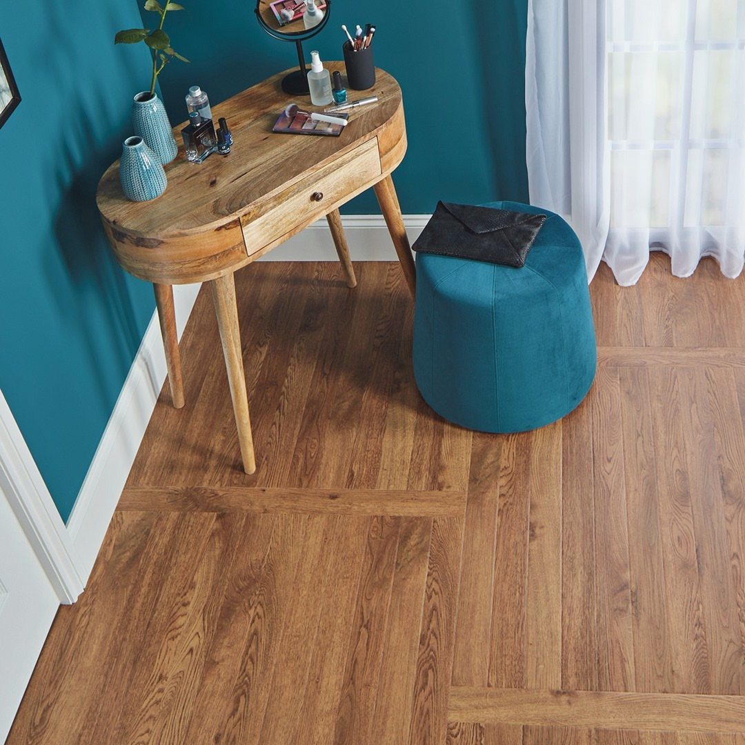 Warm oak wood flooring with a decorative border pattern in a room with teal walls.