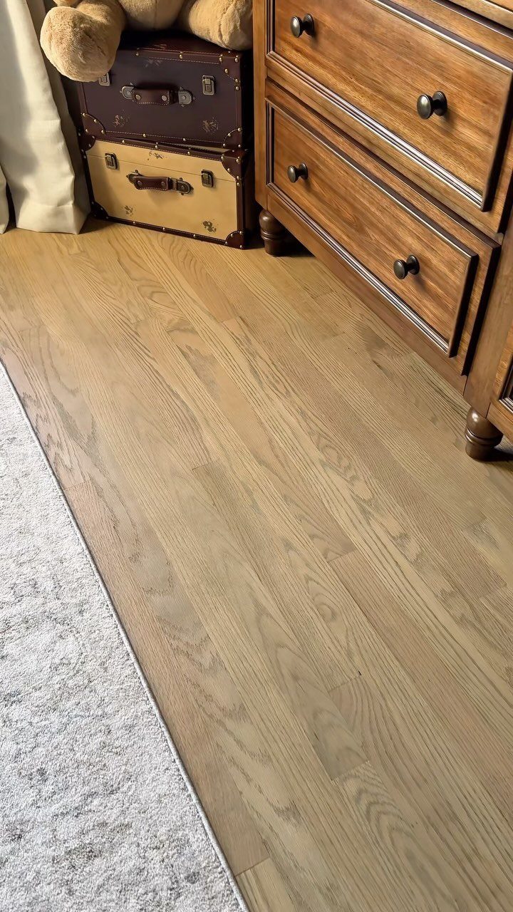Wood Floor Colors: 5 Ideas for Every Room in 2026 4 Light wood plank flooring next to a wooden dresser and vintage suitcases.