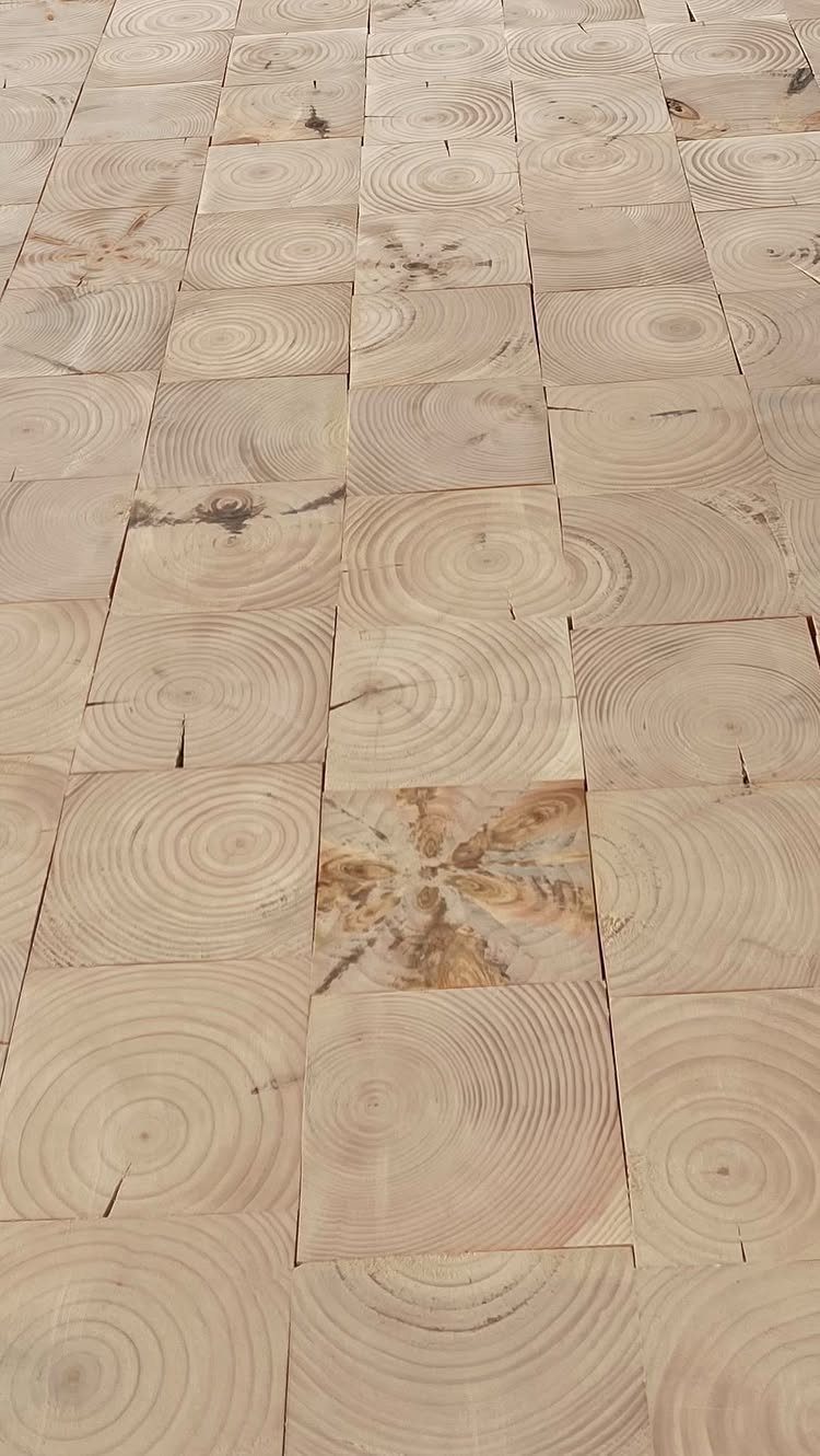 Light-colored wooden floor composed of square blocks with visible tree ring patterns.