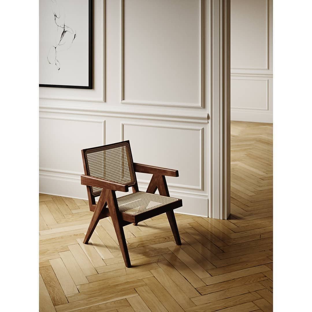 A wooden armchair placed on a light-colored herringbone patterned parquet wood floor.