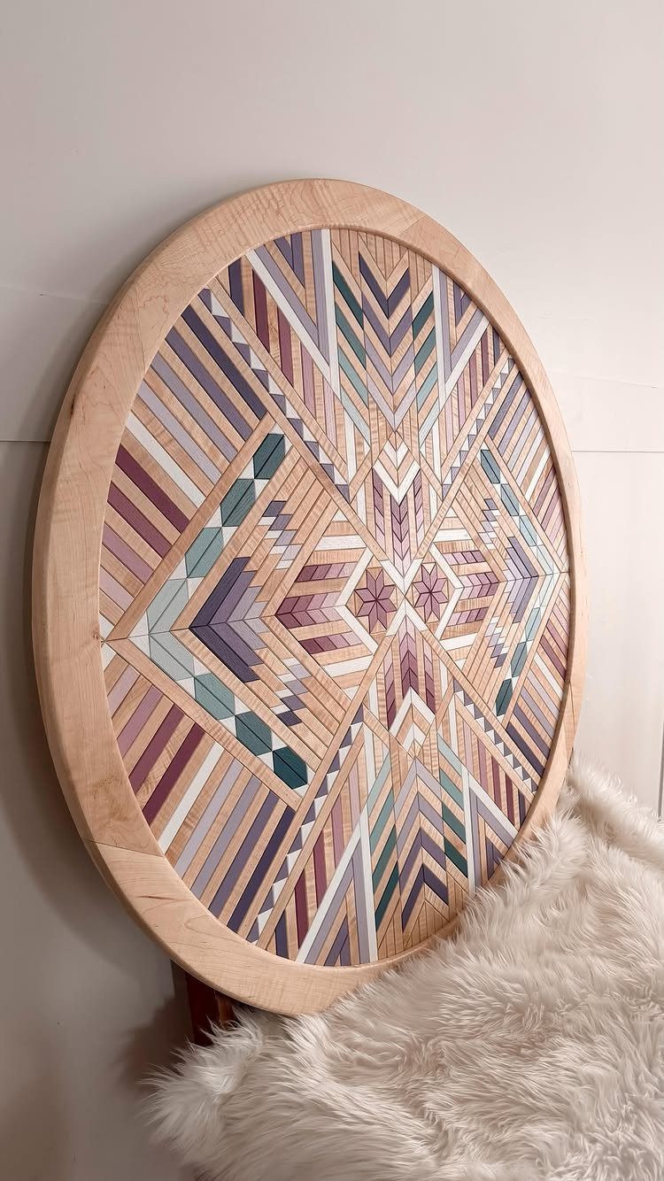 Circular geometric wood art with colorful patterned slats mounted on a white wall.