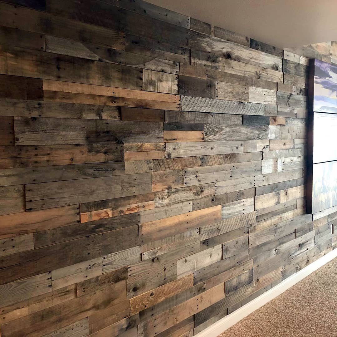 Weathered reclaimed wood planks arranged in a textured collage on a living room wall.