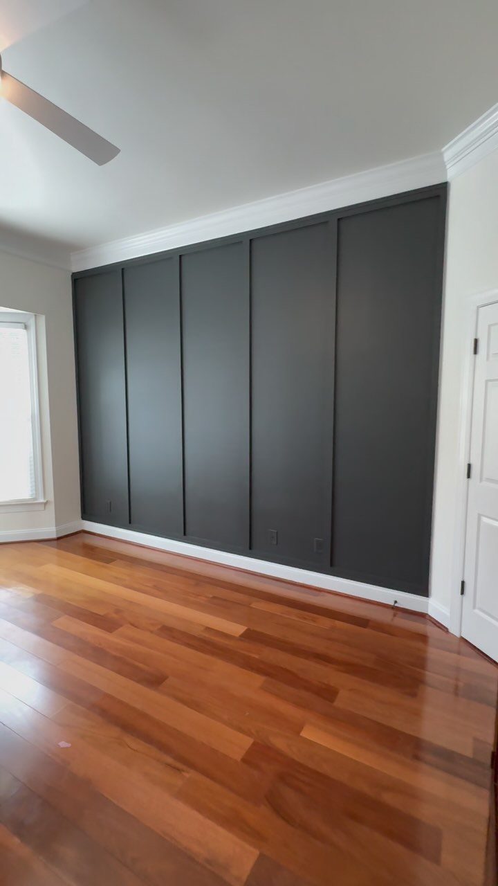 Dark grey board-and-batten accent wall in a room with hardwood floors.