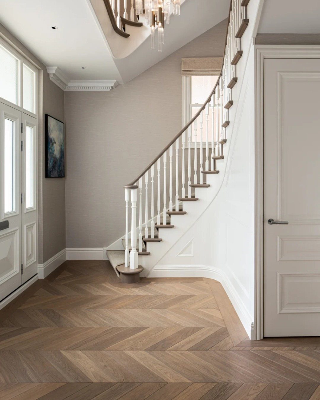 Wooden Flooring Design: 9 Ideas for Every Room 7 Chevron pattern wooden flooring in a bright, modern home entryway with a white curved staircase.