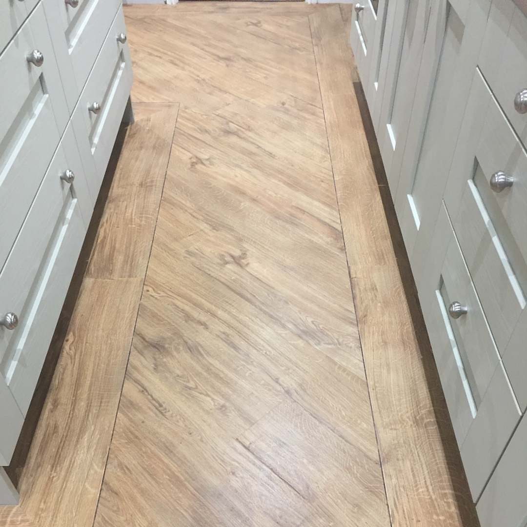 Wooden Flooring Design: 9 Ideas for Every Room 8 Light wooden planks arranged in a diagonal pattern on a floor between white cabinets.