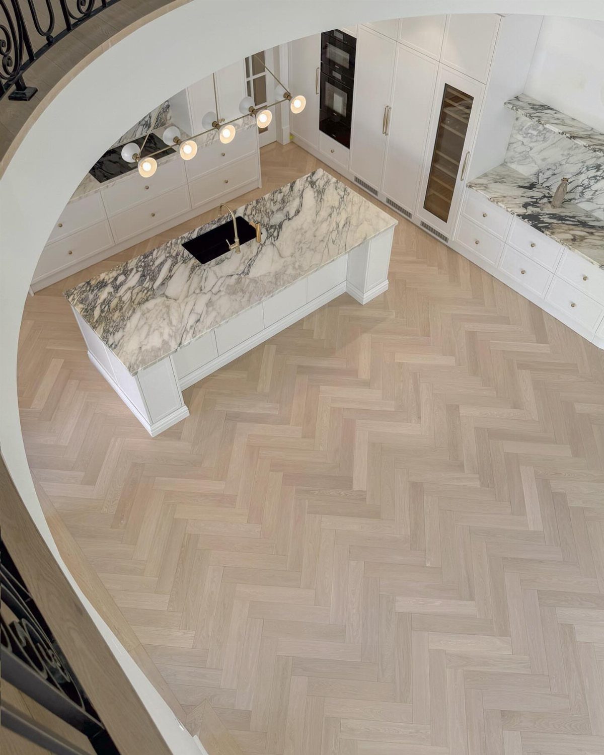 Wooden Flooring Design: 9 Ideas for Every Room 5 Light wood flooring in a herringbone pattern covers the floor of a modern white kitchen.