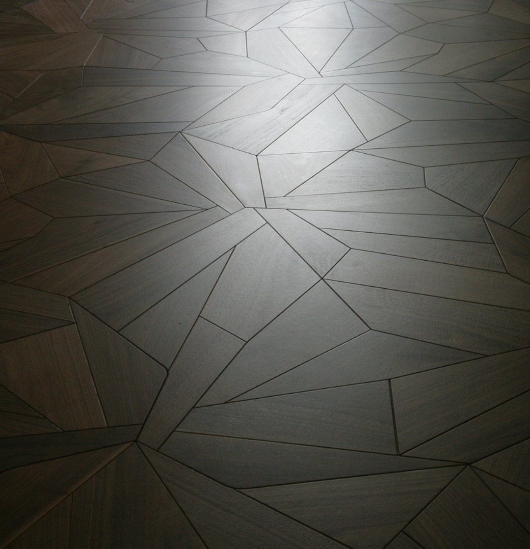 Dark wooden floor planks arranged in an irregular geometric mosaic pattern.
