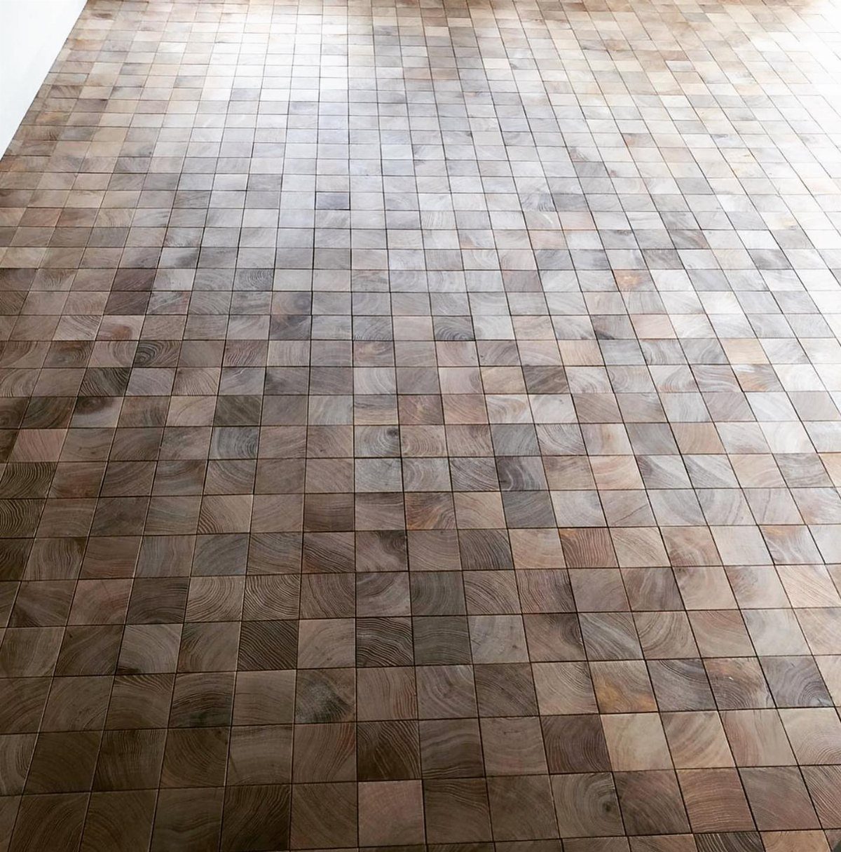 Small square wooden floor tiles arranged in a mosaic pattern with varying brown tones.