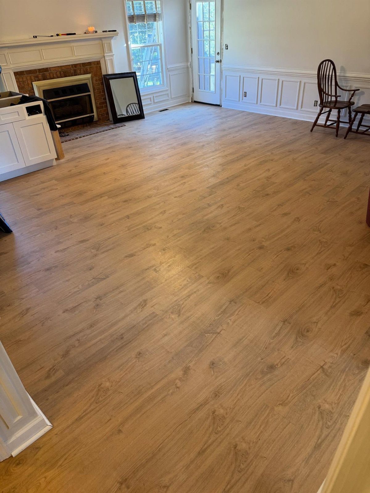 Light brown wood planks installed in a room with white walls and a fireplace.