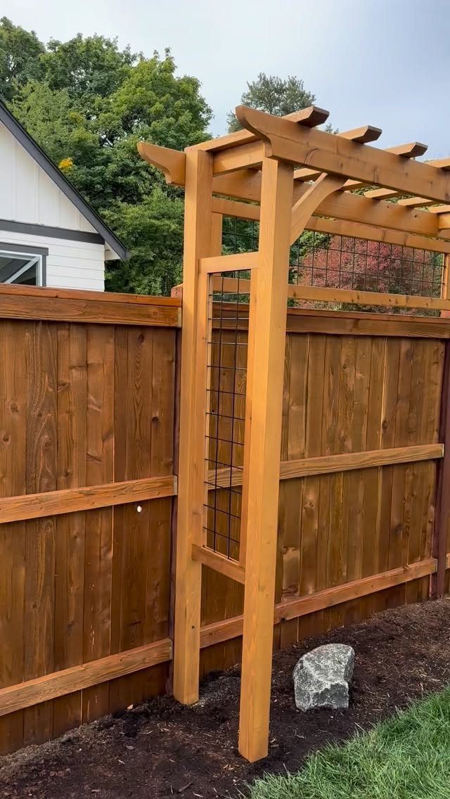 Wooden Privacy Fence: 12 Ideas That Define Your Yard 8 A tall wooden privacy fence with an attached pergola structure in a backyard setting.