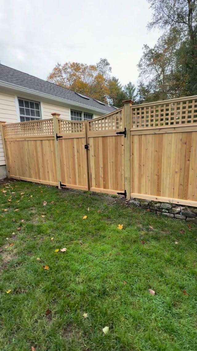 Wooden Privacy Fence: 12 Ideas That Define Your Yard 3 A wooden privacy fence with a decorative lattice top panel installed in a backyard lawn.