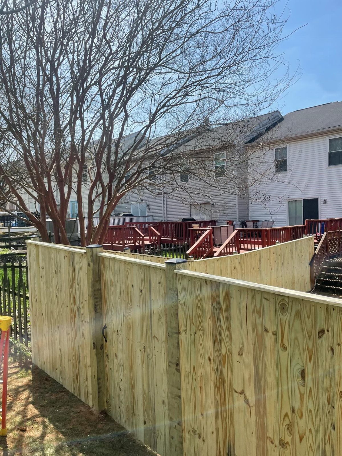 Wooden Privacy Fence: 12 Ideas That Define Your Yard 5 A new wooden vertical board privacy fence in a residential backyard setting.